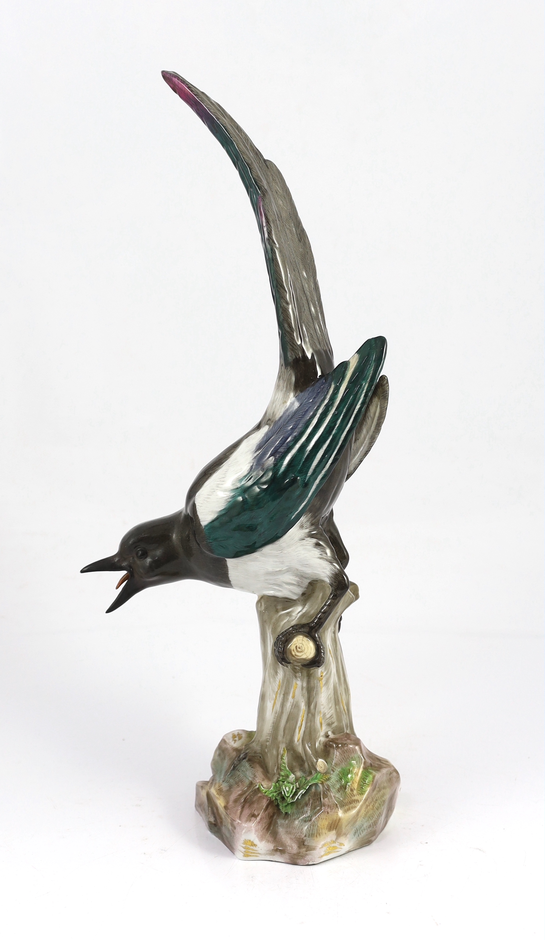 A tall Meissen figure of a magpie, 19th century, perched on a tree stump, incised model no. 62, underglaze blue crossed swords mark, 50cm high, restoration to beak and one wing tip